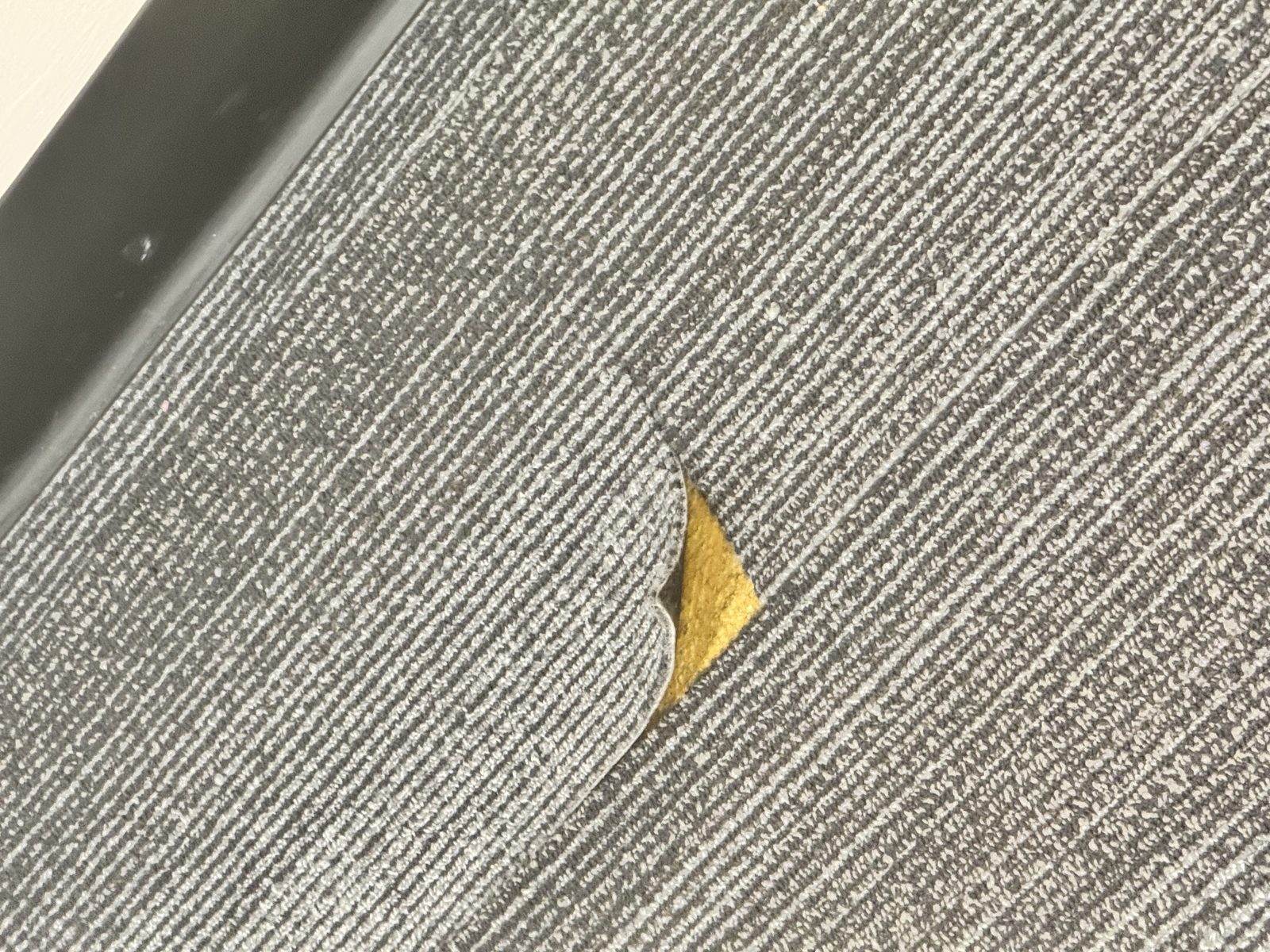 Corner edge lifting on a glue-down modular carpet tile in a commercial building